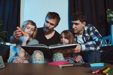 Staged photo. Homosexual couple and their children, two cute girls, at home.   All are excitedly...