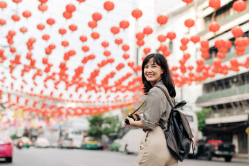 Obraz premium Young Asian woman backpack traveler enjoying China town street food market in Bangkok, Thailand. Traveler checking out side streets.
