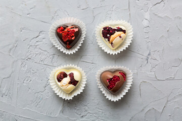 chocolate sweets in the form of a heart with fruits and nuts on a colored background. top view with space for text, holiday concept