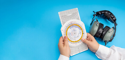 Women's hands hold an aviation navigation computer on the background of a headset as a concept for training female pilots.