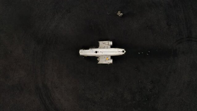 Aerial: Top down shot of one person standing on the right wing of DC3 plane wreck in Iceland