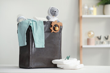 Mother's bag with baby's stuff on white wooden table indoors. Space for text