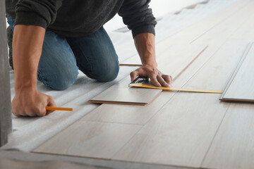 Worker installing new laminate flooring in room, closeup