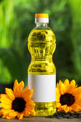 Bottle of cooking oil, sunflowers and seeds on wooden table against blurred background