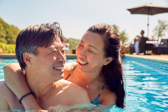 Loving Mature Couple Hugging In Swimming Pool On Summer Vacation  - Powered by Adobe