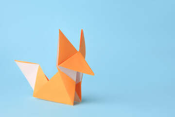 Origami art. Handmade orange paper fox on light blue background, space for text