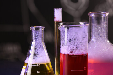 Laboratory glassware with colorful liquids on blurred background, closeup. Chemical reaction