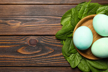 Naturally painted Easter eggs and space for text on wooden table, flat lay. Spinach used for coloring