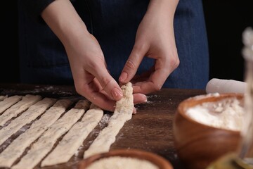 Woman making grissini at wooden table, closeup