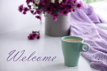 Welcome card. Cup of aromatic coffee, beautiful flowers and violet cloth on white table