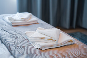 Towels stacked on a bed in the bedroom and prepared for tourists. Clean white towel in a hotel room.