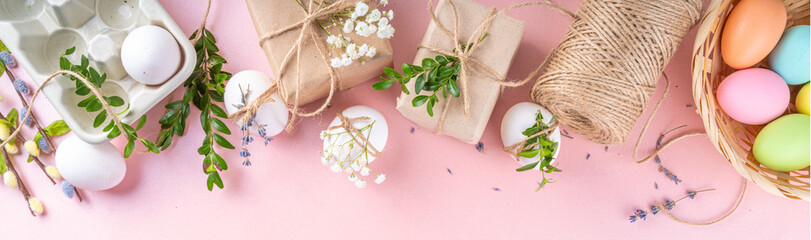 Eco friendly zero waste Easter flatlay. Spring flowers, leaves, eggs on pink pastel background, with craft paper gift box. Woman hands decorate eggs with organic natural decor, preparation for Easter