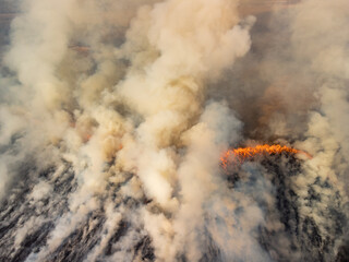 Drone photo of clouds of smoke and fire in the field. Concept of field fire early in spring due to dry weather