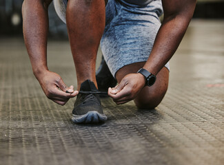Hands, fitness and tie shoes in gym to start workout, training or exercise for wellness. Sports, athlete health and black man tying sneakers or footwear laces to get ready for exercising or running.