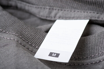 Close up on empty label of a gray t-shirt of M size. New shirt with copy space on its label