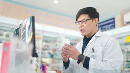 Asian male pharmacist talkin with customer on computer online counseling and discusses choice of medication in drugstore - Powered by Adobe