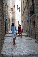 Fototapeta na wymiar two women travel through an old town in Italy. concept immersive travel. walking in the street