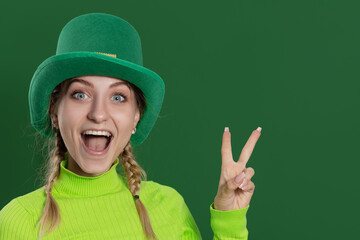 St. Patrick's Day leprechaun model girl in green hat, funny clover shaped sunglasses, isolated on green background and smiling, having fun. Patrick Day pub party, celebrating.