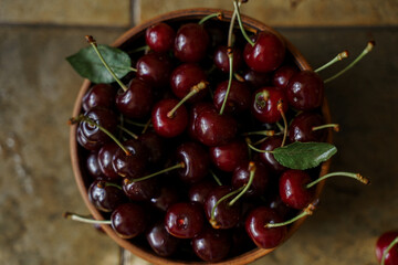 Ripe red cherries in a wooden bowl on a wooden background