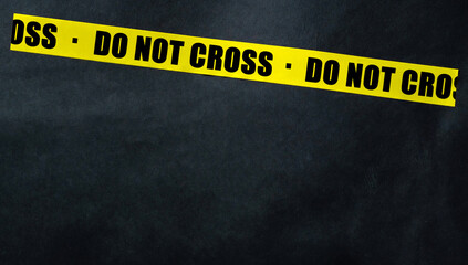 Yellow tape with text Do Not Cross on a dark background. Warning ribbon.