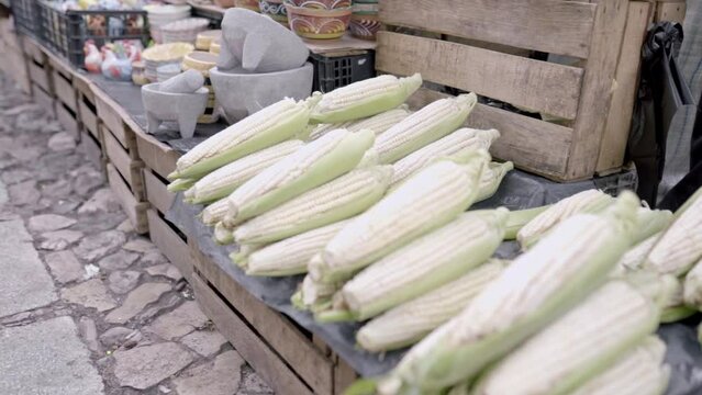 Some corn cobs are displayed in wooden stall in a Mexican street market