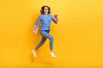 Fototapeta na wymiar Full length profile portrait of crazy person jumping rush hold netbook coffee mug isolated on yellow color background