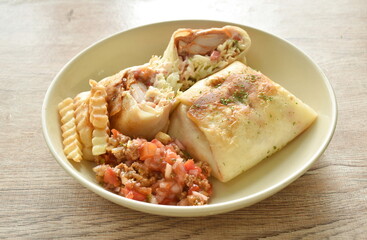 burrito Mexican food stuffed chicken and cabbage coleslaw dressing with chop tomato in sauce sauce and French fries on plate