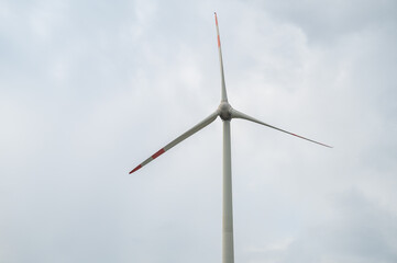 Modern wind turbine renewable energy during daylight with cloudy sky, view from low angle