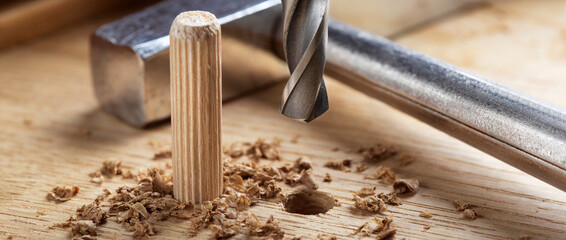 drill bit makes hole in wooden oak board for wooden dowel.