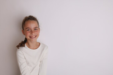 Fototapeta premium Little emotional teen girl in white shirt 11, 12 years old on an isolated white background. Children's studio portrait. Place text, to copy space for inscription, advertising children's goods.