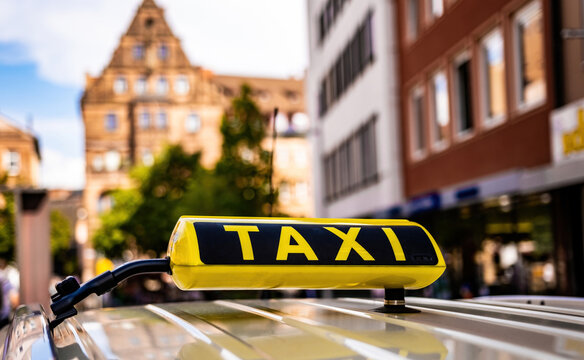 Yellow taxi sign in old historical town of Germany closeup. Cab service board on car at ancient europen city street