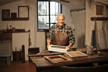Obraz na płótnie Canvas senior craftsman works in his paper workshop