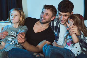 Staged photo. A homosexual couple and their children, two cute girls, at home.  The whole family is...