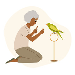 Elderly woman teaches her parrot to talk and gives a treat to bird. The owner spends time with pet.