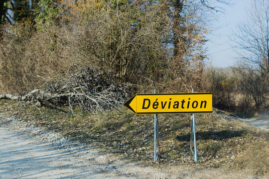 Diversion sign on the forest gravel road in a France shows to left.