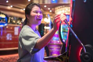 exited asia female woman slot machine gambling cheerful smile hand pressing bet button in casino club entertainment concept,exited asian woman hand play slot machine in casino hotel