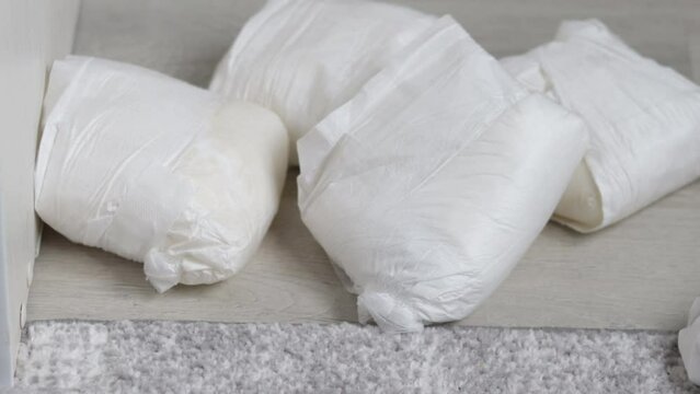 many dirty full baby diapers on floor bed or in blue trash plastic bag,woman hand putting on.small mini trash bin with diapers,carpet room interior.ecology concept,maternity recycle sorting garbage.