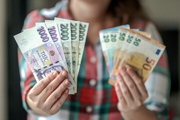 person holding euro banknostes in one hand and in second hand czech crown banknotes of different value - obrazy, fototapety, plakaty