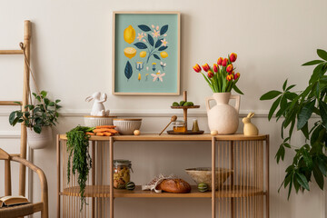 Warm and cozy composition of easter living room interior with mock up poster frame, vase with tulips, hare sculpture, carrot, bowl, wooden sideboard and personal accessories. Home decor. Template.