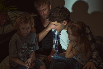 Staged photo. Homosexual couple and their children, two cute girls, at home.  Scary movies are best...