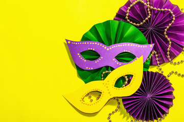 Festive Mardi Gras masquerade yellow background. Fat Tuesday carnival, masks, beads, traditional decor