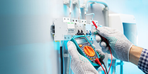 Electrician engineer work tester measuring voltage and current of power electric line in electrical panel. Banner with copy space.