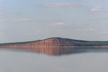 lake with a mountain reflection, red hill with forest on background