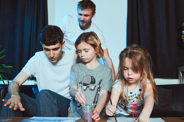 Staged photo. Homosexual couple and their children at home.  The girls drew beautiful pictures. Watercolors are the best choice for beginning painters.