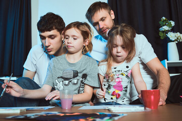 Staged photo. Homosexual couple and their children at home. Watercolors are the best choice for amateurs! Children need their parents' approval when learning new things.