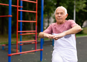 Old man warming up before training outdoors