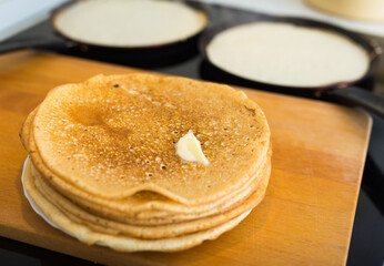 process of baking pancakes in pans on kitchen stove. stack of hot pancakes