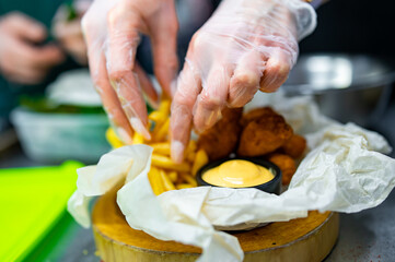 woman chef cooking Chicken Nuggets with French Fries and sauce on kitchen