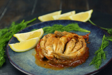 sprat fish in tomato sauce on the plate with lemon slices and dill closeup photo