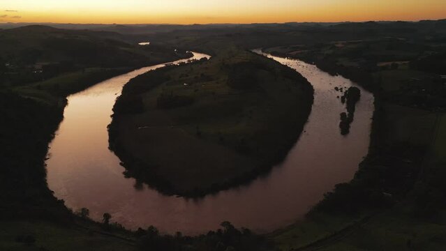 Aerial view of winding river at sunset amid green fields and forest. Volta do Dedo. Chapec&oacute; river. 4K.